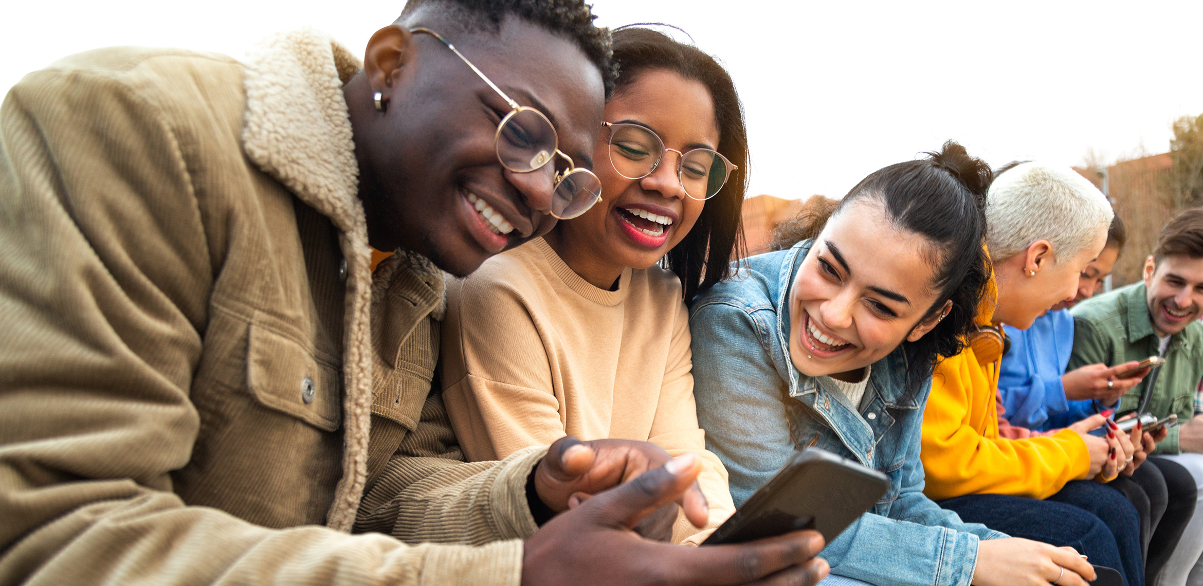 Un groupe de jeunes munis de smartphones rit et discute.