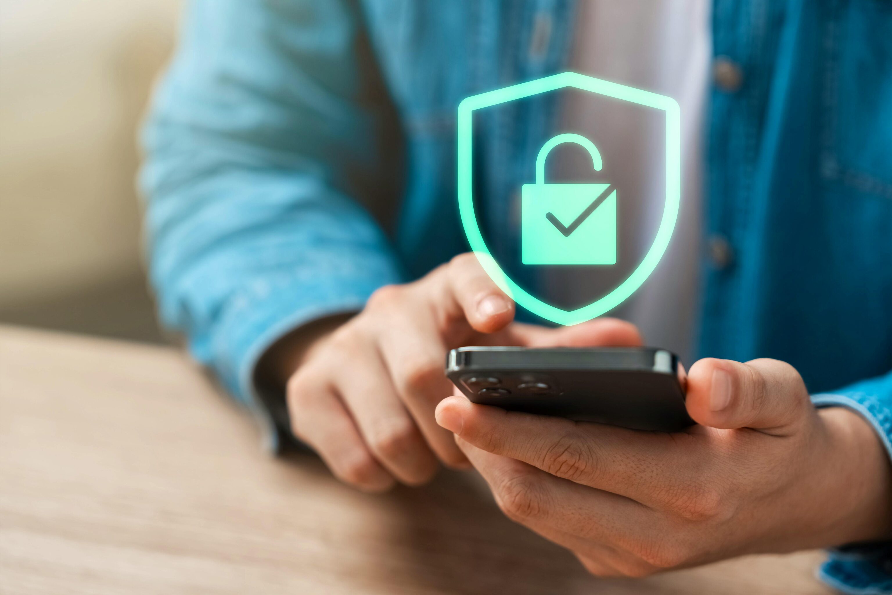 Eine Person tippt auf ein Smartphone. Darüber erscheint ein digitales Schloss mit Häkchen, Symbol für Datenschutz und Sicherheit.