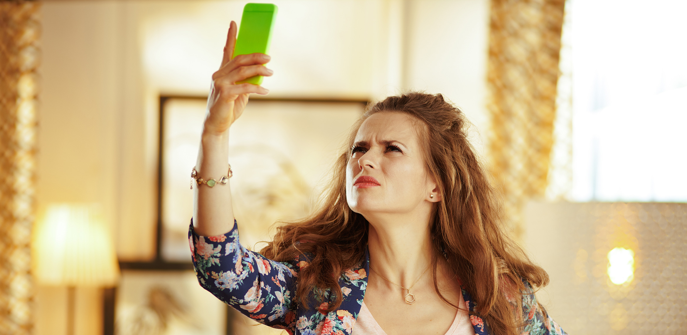 Frau hebt ihr Smartphone in die Höhe und schaut genervt – sie sucht nach Empfang.