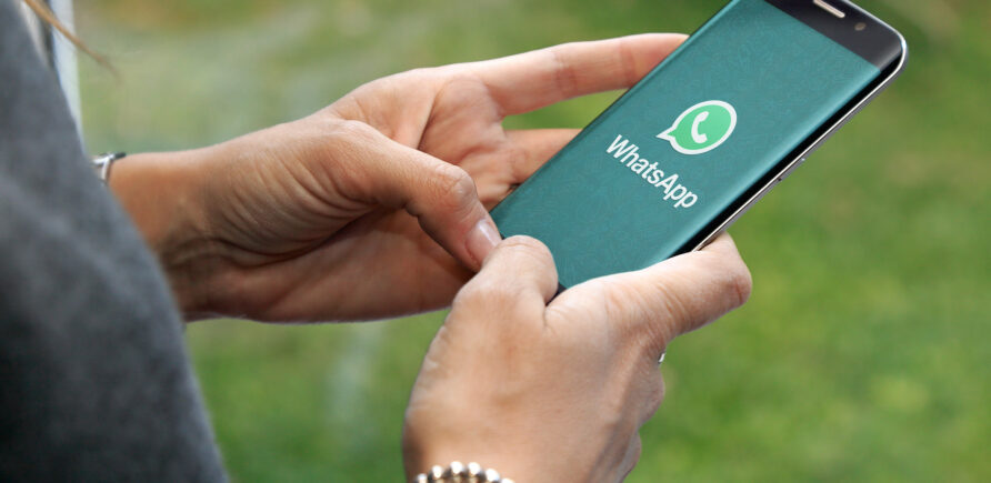 Une femme utilise WhatsApp sur son smartphone et affiche un air sceptique.