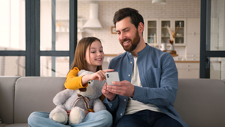Kind und erwachsene Begleitperson richten gemeinsam ein Smartphone für den Schulalltag ein.